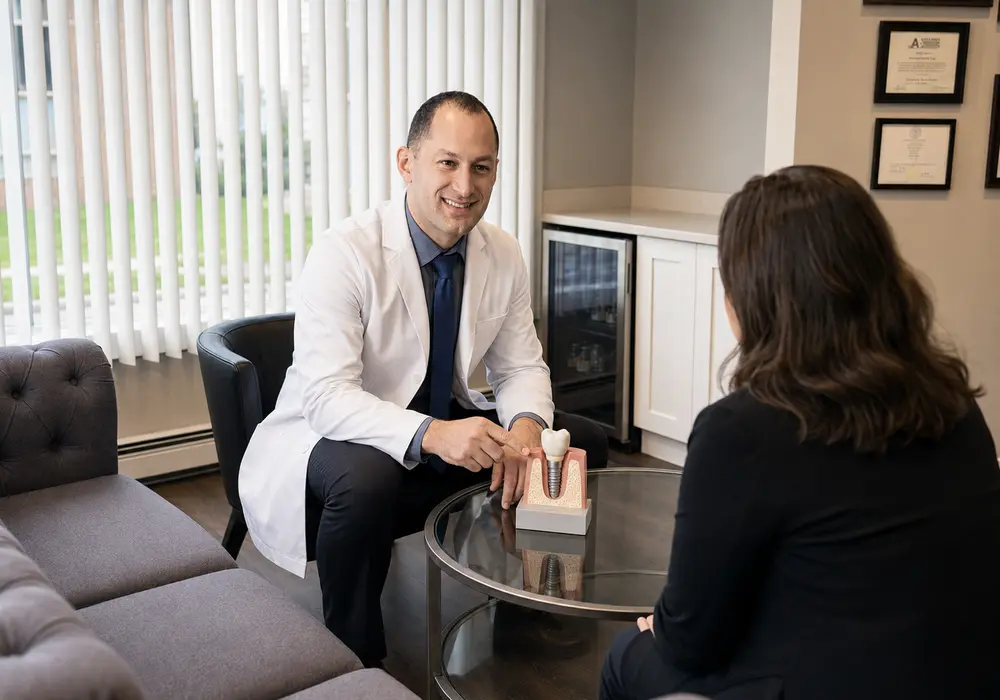 Dr. Mady explaining a dental implant model to a patient in his consultation lounge